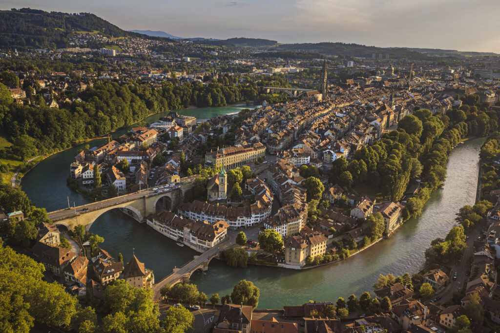 Die Altstadt liegt auf einer Flussschleife der Aare mit Brücken und dichtem Häusermeer im warmen Licht.