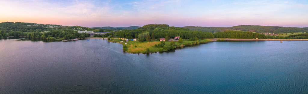 Panorama über den Bostalsee mit grünen Ufern und sanften Hügeln.