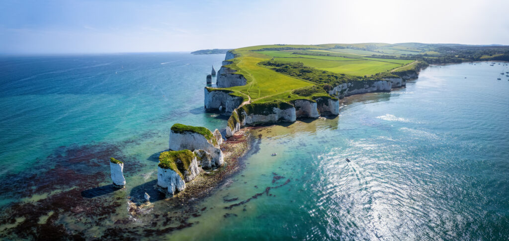 Luftaufnahme der Old Harry Rocks mit weißen Felsen, grünem Kliff und blauem Meer in Dorset.