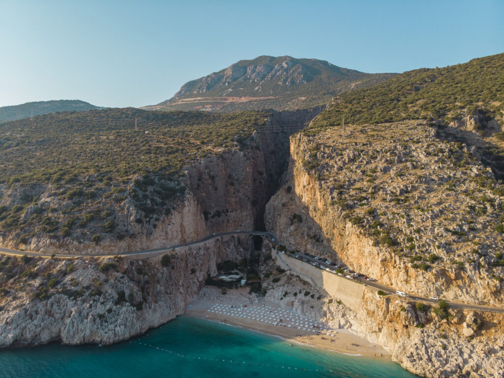 Blick auf die kleine Bucht von Kaputaş Beach mit türkisfarbenem Wasser unter steilen Felsen.