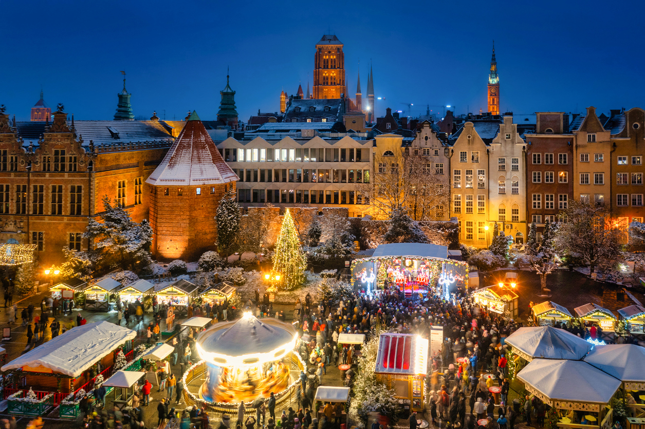 Weihnachtsmarkt in Danzig bei Nacht mit Lichtern und Karussell.