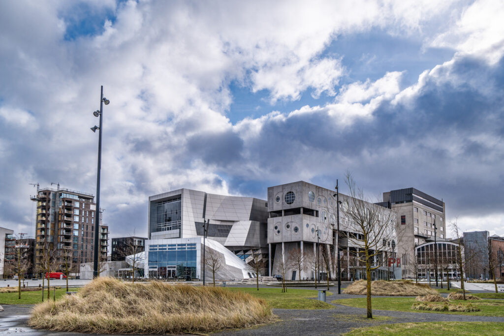Futuristisches Gebäudeensemble mit Glasfassaden unter dramatischem Himmel in Aalborg.
