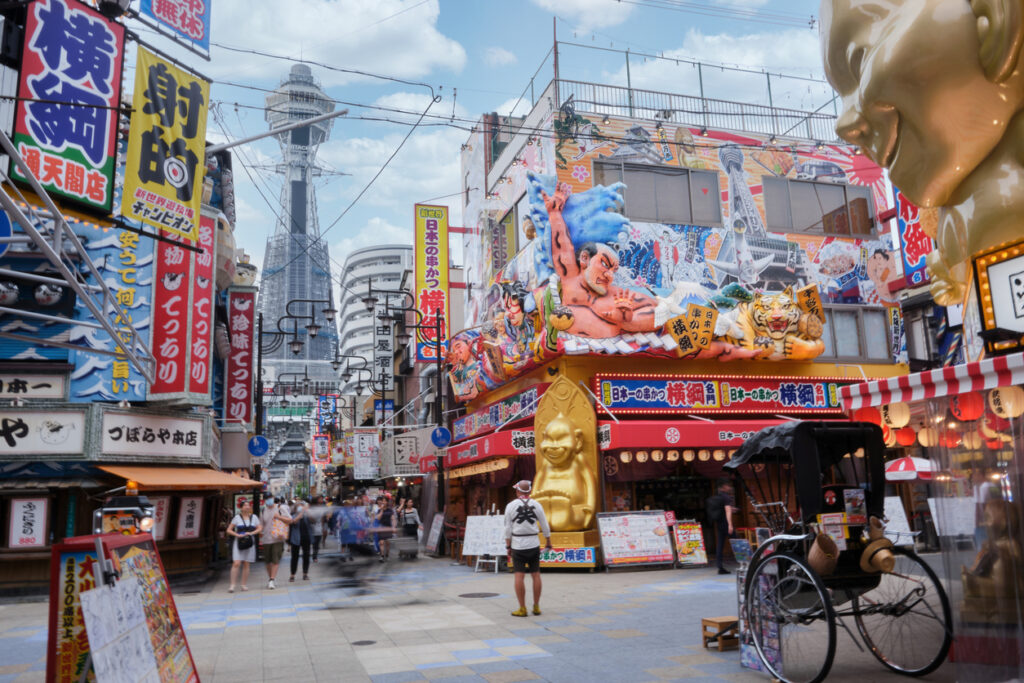 Bunte Reklame und der Tsutenkaku-Turm prägen das belebte Shinsekai-Viertel in Osaka.
