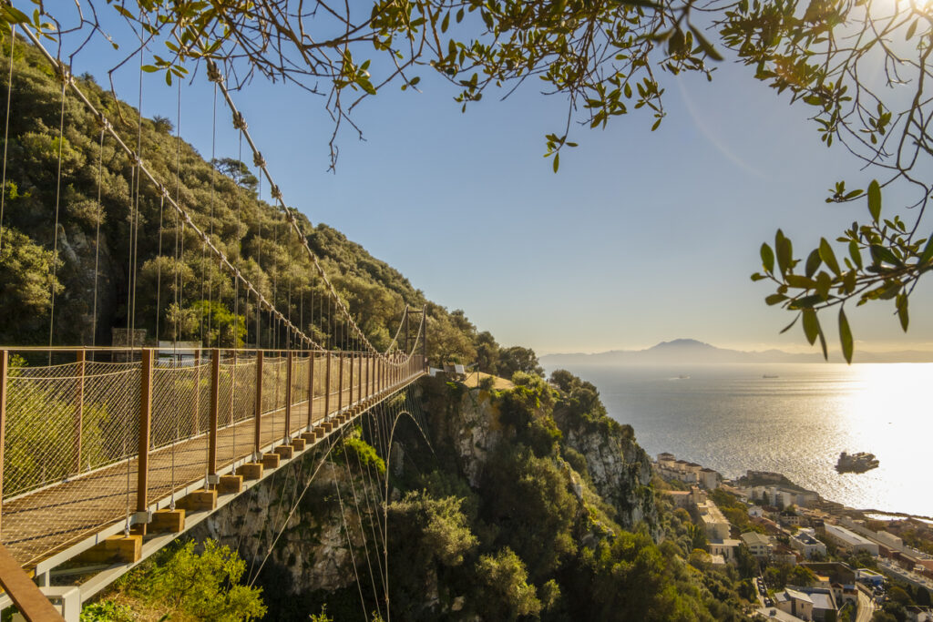 Eine Hängebrücke in Gibraltar spannt sich über eine Schlucht mit Blick Richtung Küste.
