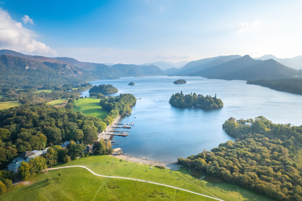 Weite Seenlandschaft mit grünen Ufern, Inseln und Bergen im Lake District National Park.