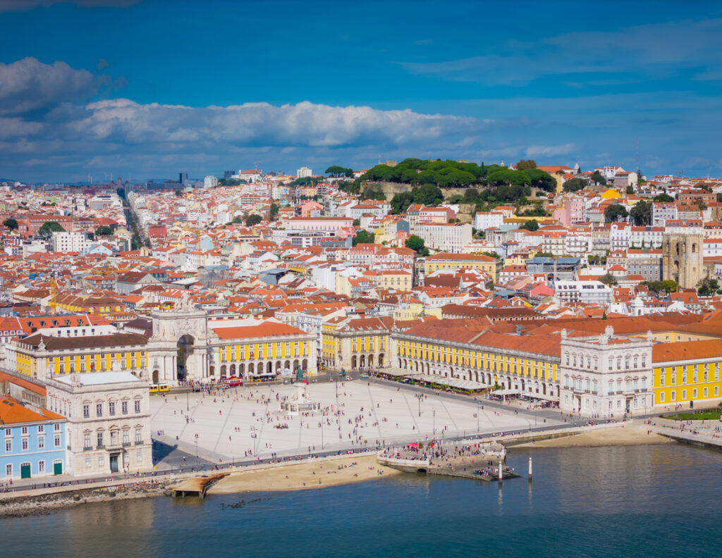 Die Praça do Comércio in Lissabon liegt am Fluss, umgeben von gelben Fassaden und einem weiten Platz.