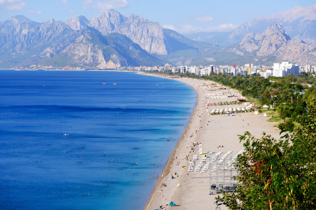 Der Konyaaltı Beach zieht sich als breiter Strand entlang der Küste vor hohen Bergen.