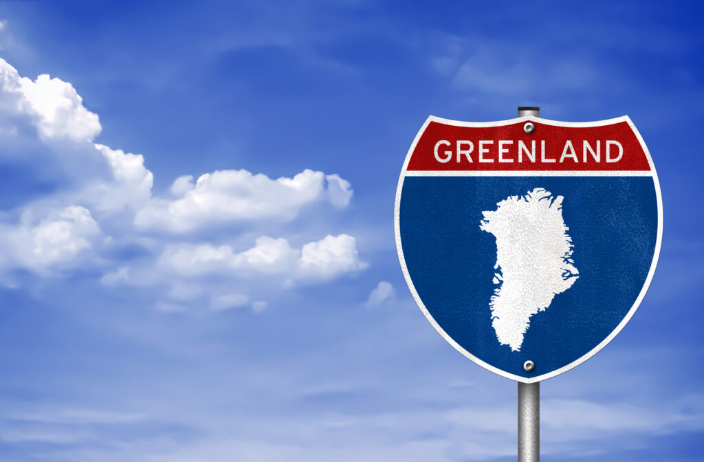 Schild mit der Aufschrift Greenland und einer weißen Insel Silhouette vor blauem Himmel.