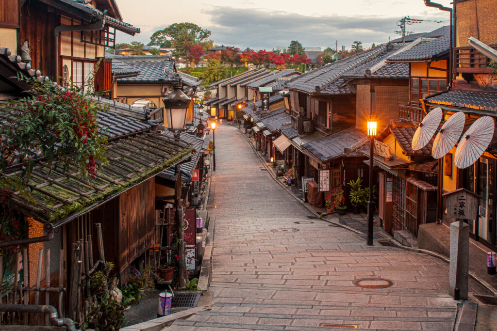 Eine steinerne Gasse in Kyoto führt zwischen traditionellen Holzhäusern bergab.