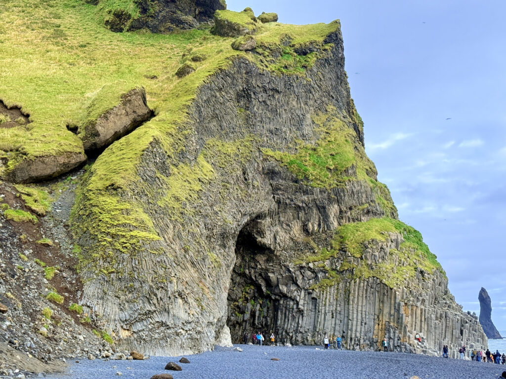 Mächtige Basaltsäulen und eine Höhle am schwarzen Sandstrand in Island.