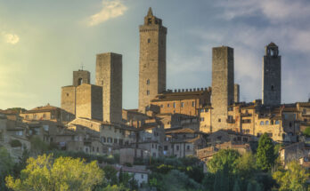 Hohe Steintürme ragen über einer Altstadt in der Toskana auf.