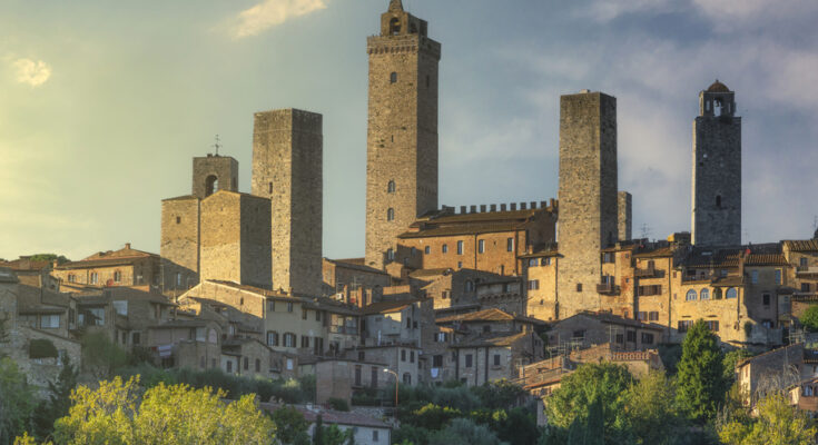 Hohe Steintürme ragen über einer Altstadt in der Toskana auf.