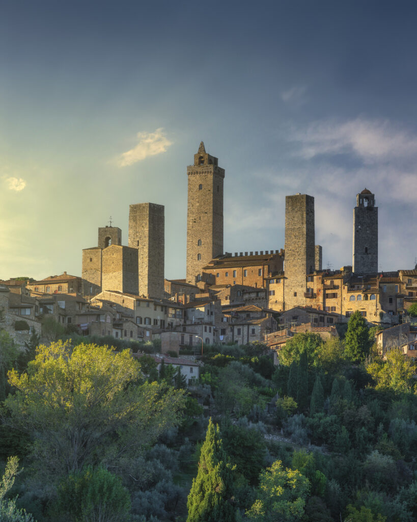 Hohe Steintürme ragen über einer Altstadt in der Toskana auf.
