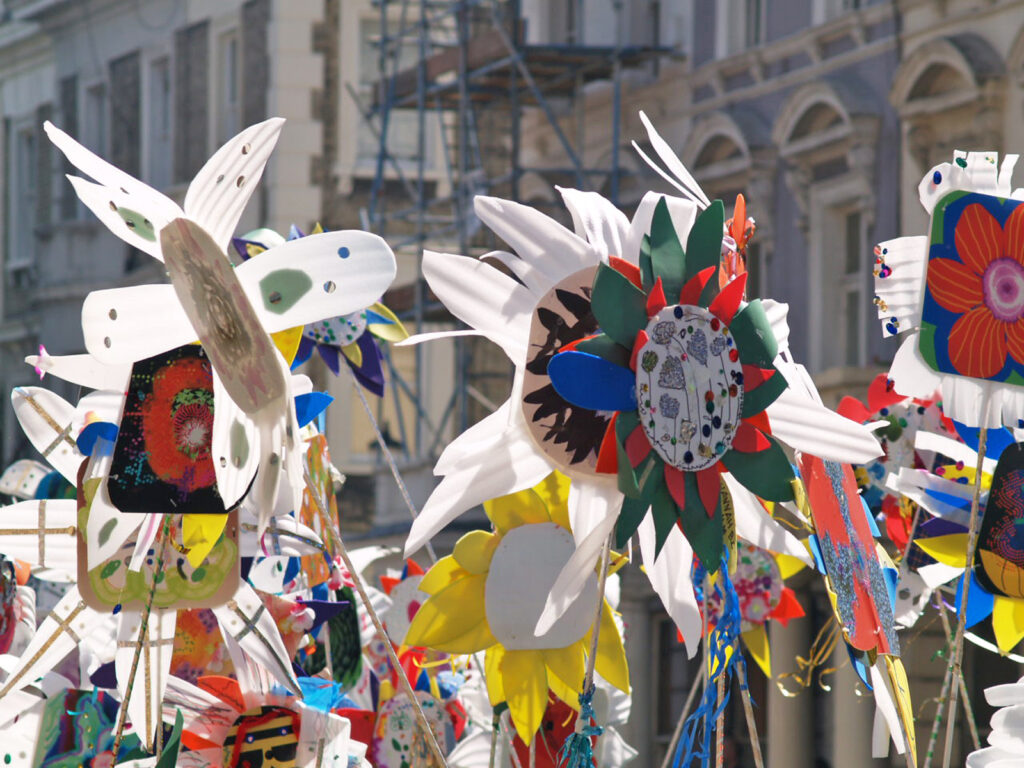 Bunte Karnevalsflaggen und Dekorationen hängen dicht gedrängt vor Häuserfassaden in London.