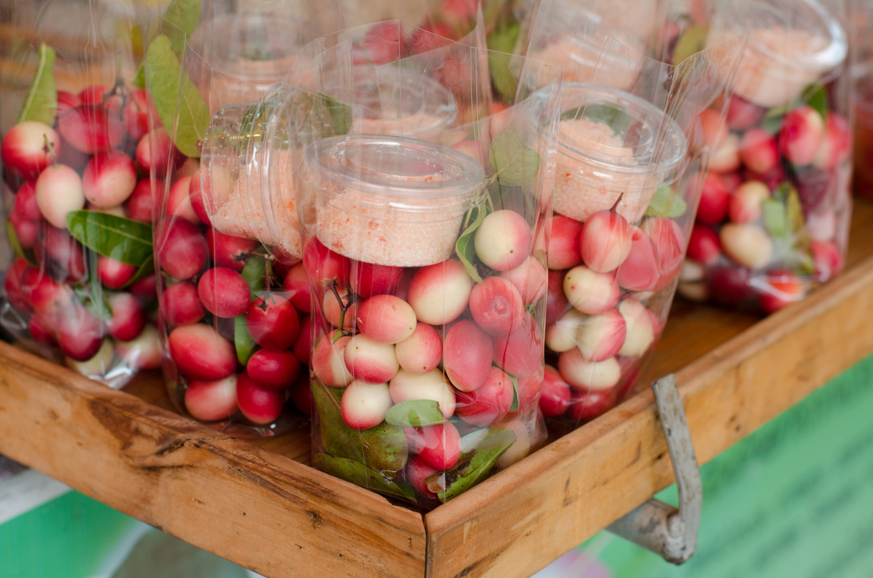 Snack-Portionen mit rot-weißen Früchten und Chili-Salz in Plastiktüten am Amphawa Floating Market in Thailand.