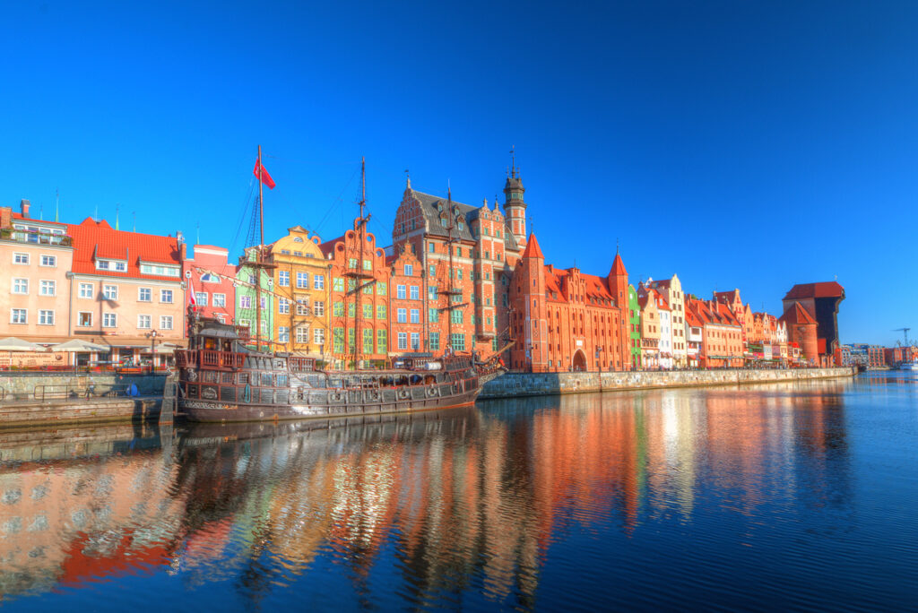 Bunte Häuserfront an der Mottlau in Danzig mit historischem Schiff.
