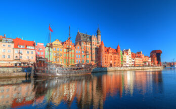 Bunte Häuserfront an der Mottlau in Danzig mit historischem Schiff.