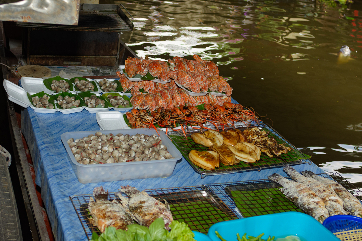 Gegrillte Krabben, Muscheln und Fisch auf einem Bootstand am Taling Chan Floating Market in Bangkok.