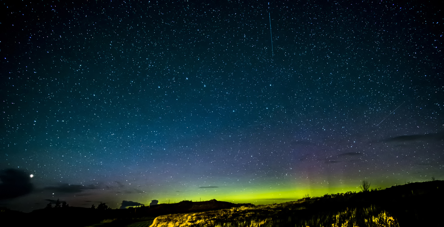 Ein sternklarer Himmel über Skye zeigt einen grünen Nordlichter-Schimmer am Horizont.