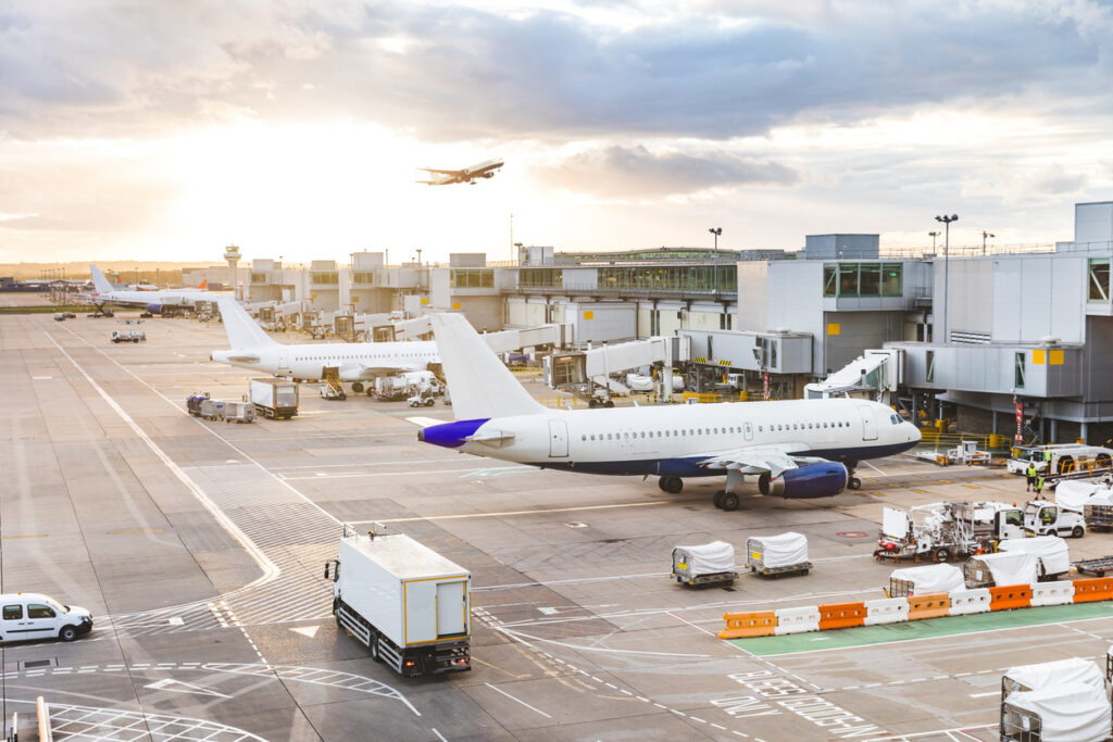 Flugzeuge stehen am Terminal, während Bodenfahrzeuge Gepäck und Fracht bewegen.
