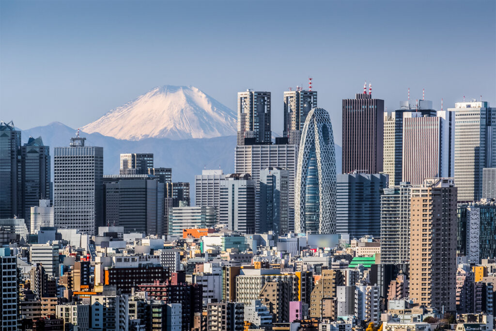 Blick über die Hochhäuser von Tokyo mit dem schneebedeckten Mount Fuji am Horizont.
