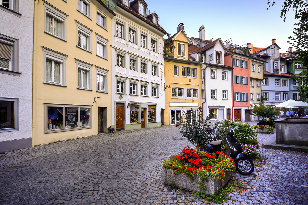 Kopfsteinpflastergasse mit bunten Häusern und Blumenbeet in Lindau.