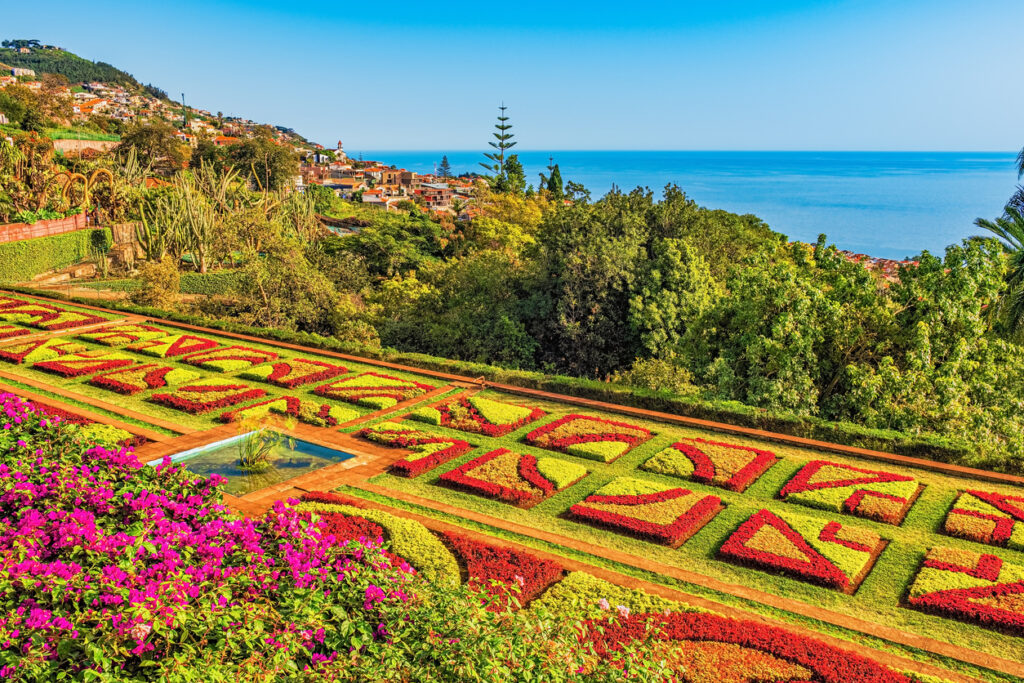 Blick über ein kunstvoll angelegtes Blumenparterre mit Meerpanorama
