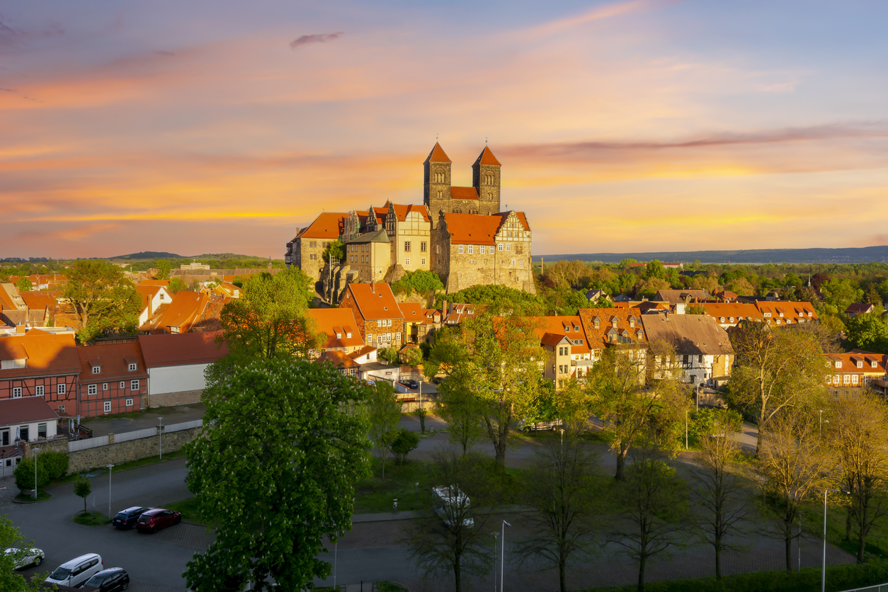 Ein Panorama zeigt Quedlinburg mit dem Schlossberg in warmem Licht der untergehenden Sonne.