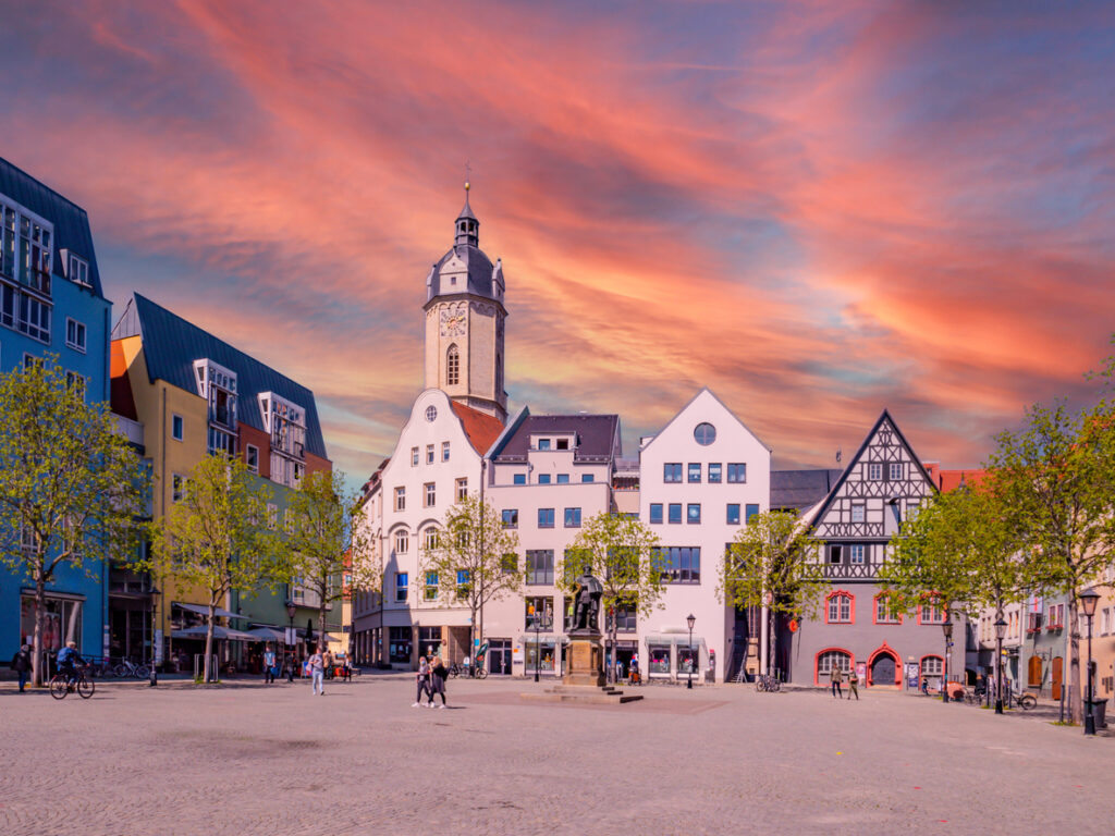 Der Marktplatz in Jena zeigt bunte Fassaden, einen Kirchturm und einen rosa Abendhimmel.