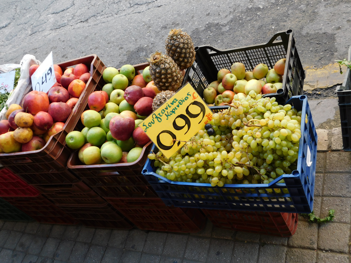 Kisten mit Trauben, Äpfeln und Pfirsichen stehen mit Preisschild an einem Markt in Patras.