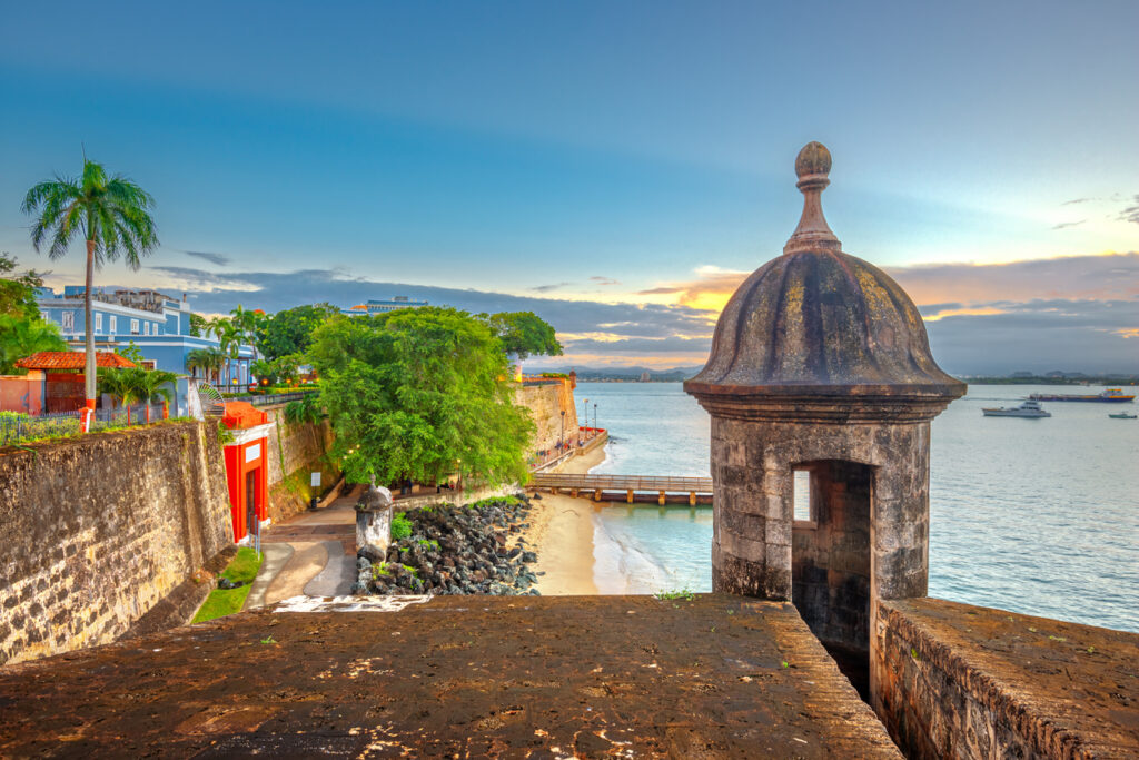 Blick auf eine historische Befestigung am Wasser bei warmem Abendlicht in Puerto Rico.