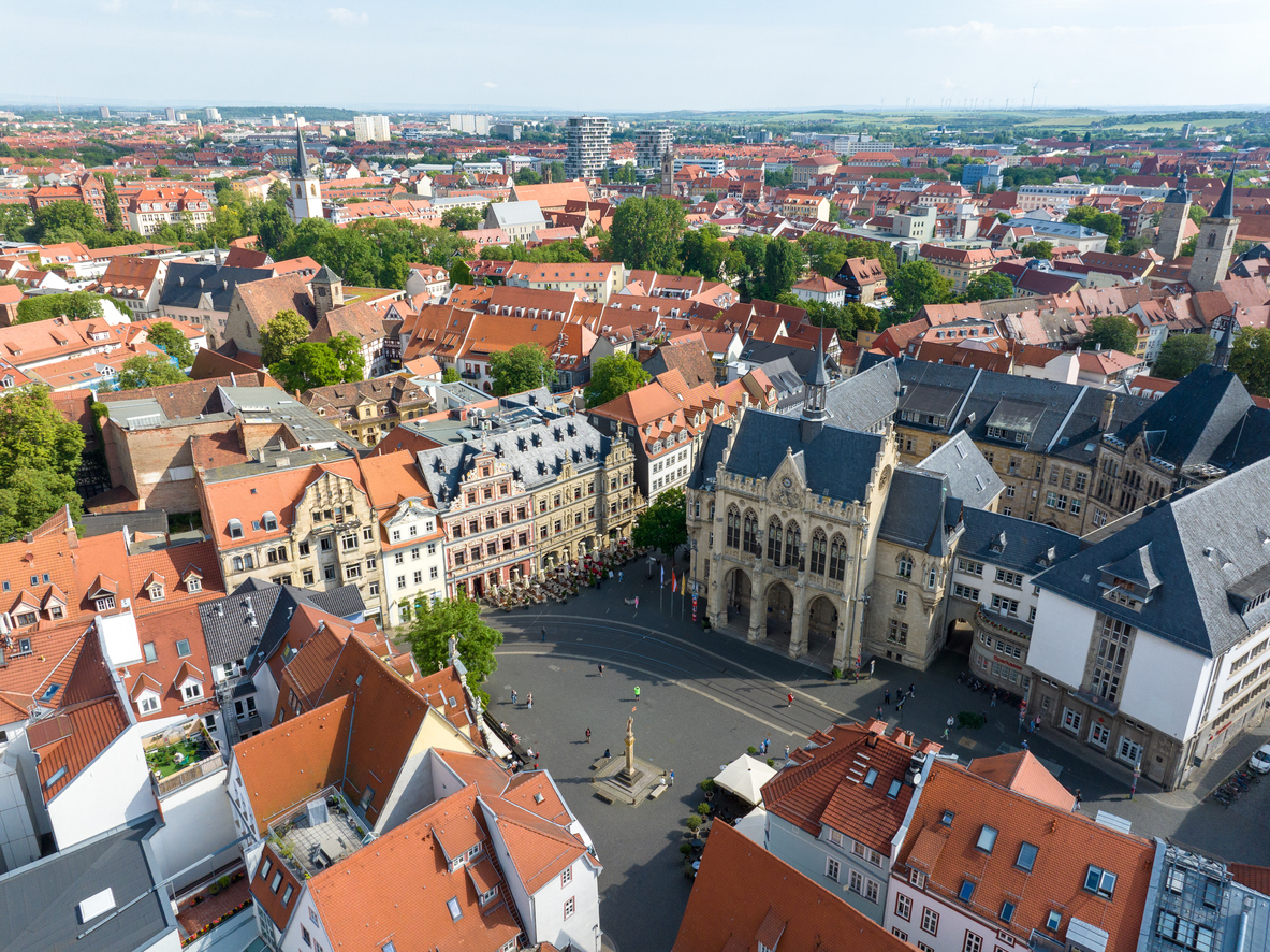 Luftaufnahme von Erfurt mit rotem Ziegeldachmeer, einem großen Platz und markanten historischen Gebäuden im Zentrum