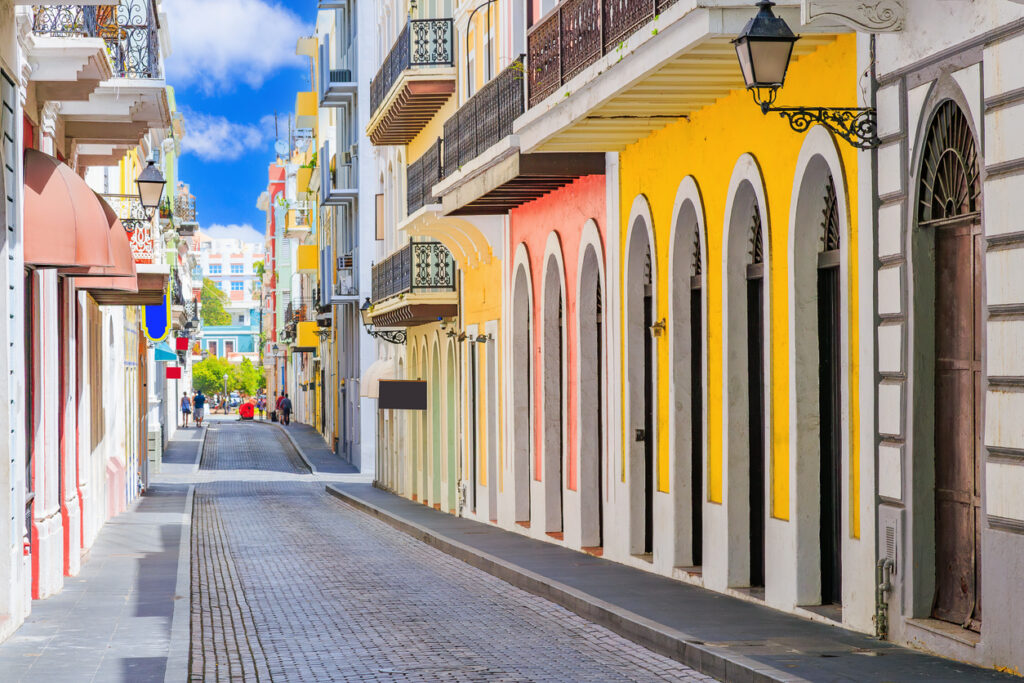 Eine schmale Gasse mit pastellfarbenen Fassaden, Balkonen und Laternen in Puerto Rico.