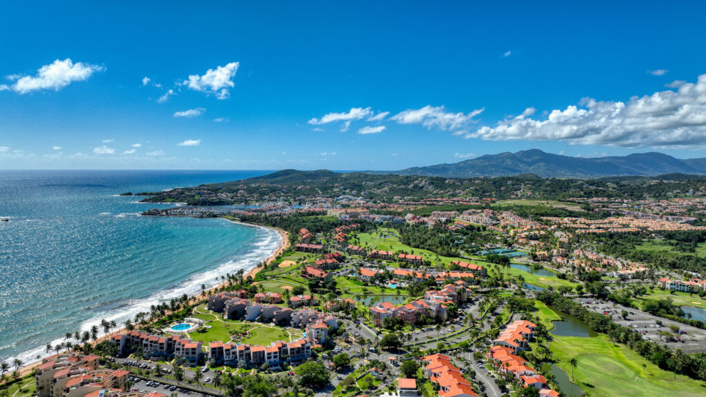 Luftaufnahme einer Küstenlinie mit Resorts, Palmen und türkisblauem Meer in Puerto Rico.