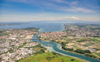 Eine Luftaufnahme zeigt Stadt, Felder und Wasserflächen, die in den See übergehen.