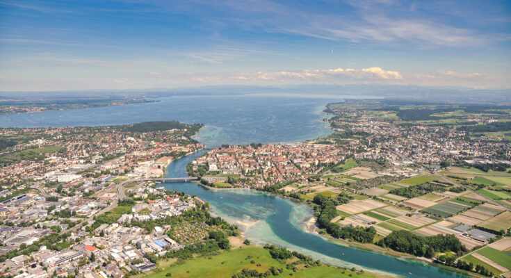 Eine Luftaufnahme zeigt Stadt, Felder und Wasserflächen, die in den See übergehen.