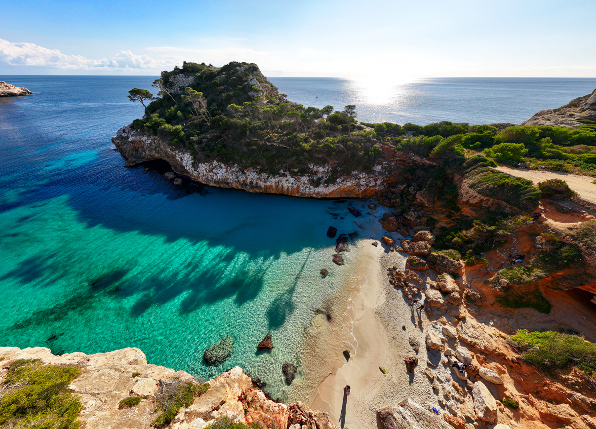 Eine kleine Bucht mit Sandstreifen, Felsen und Pinien liegt an der Küste von Mallorca.