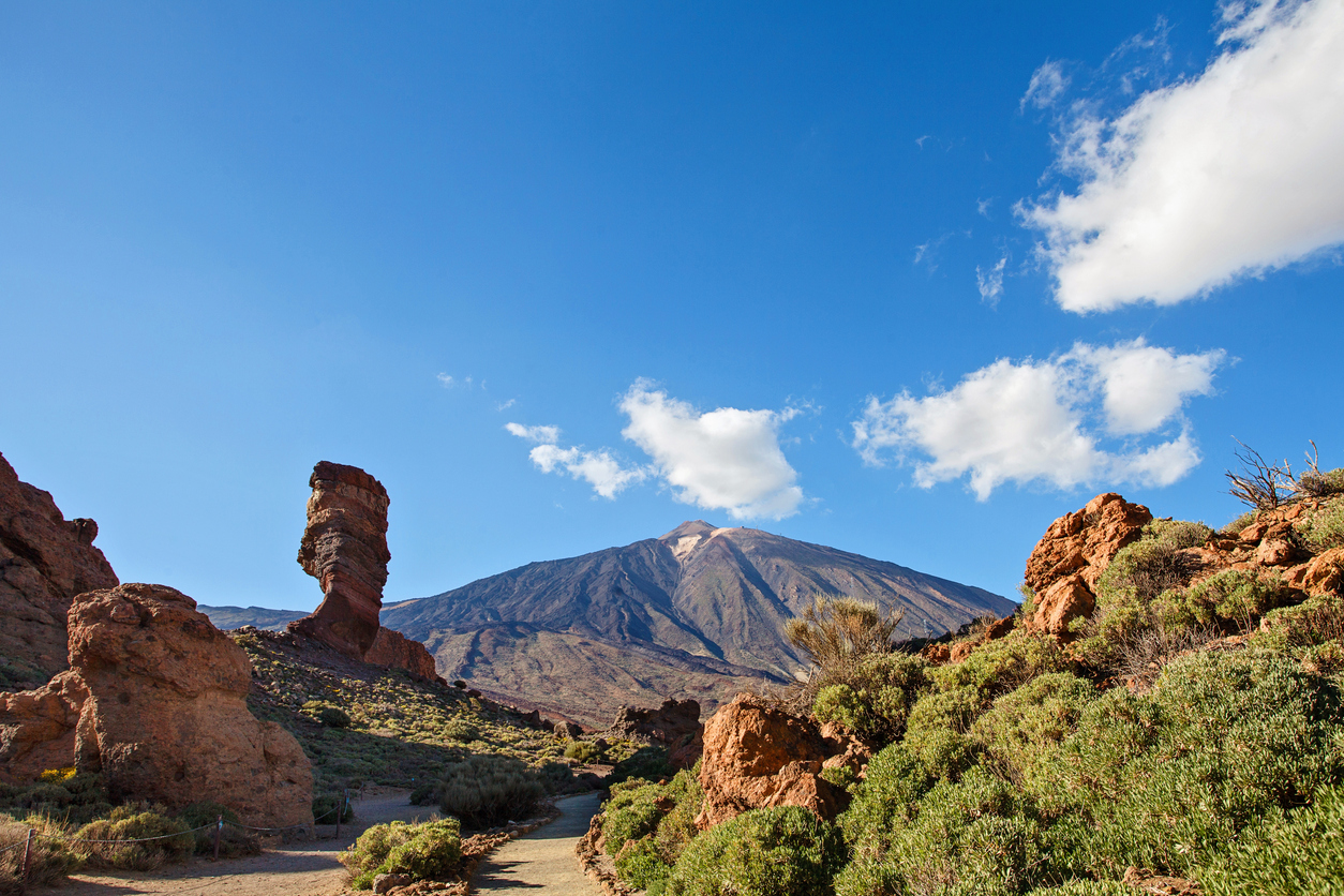 Blick auf den Teide mit Felsen, grüner Vegetation und blauem Himmel