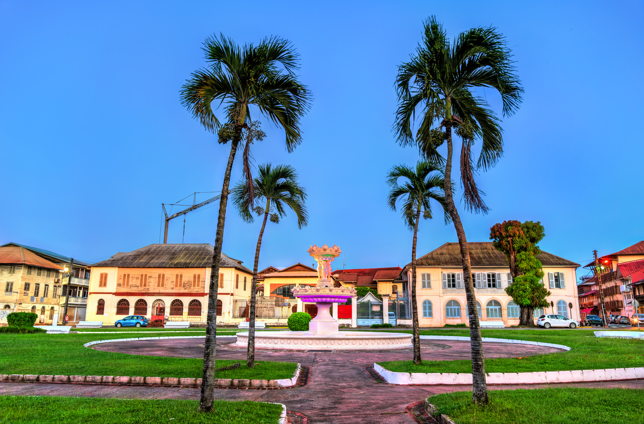Ein kleiner Platz mit Brunnen liegt zwischen Palmen und historischen Häusern im warmen Licht.