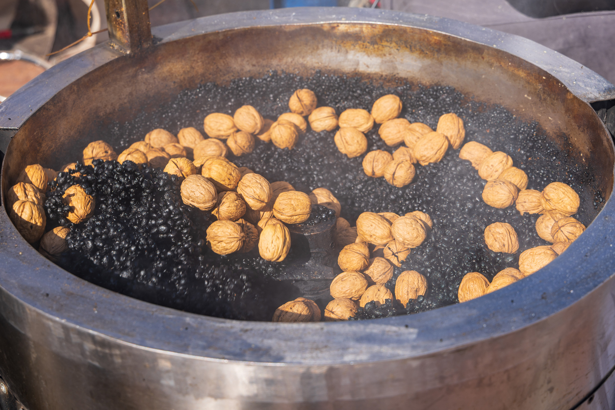 Walnüsse werden in einem großen Metallkessel in heißem Granulat geröstet.