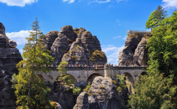 Besucher auf der Basteibrücke zwischen hohen Sandsteinfelsen in der Sächsischen Schweiz.