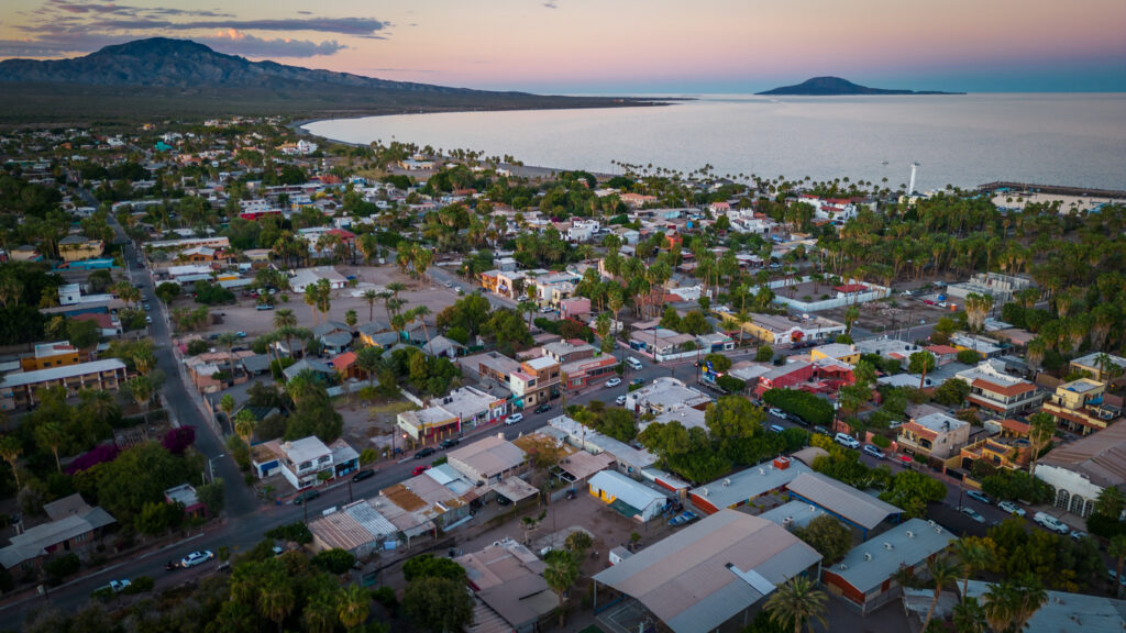 Blick über Loreto mit Palmen, Häusern und Küste bei Sonnenuntergang in Baja California Sur.