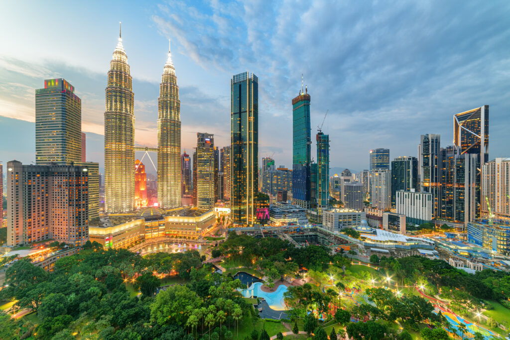 Skyline von Kuala Lumpur mit den Petronas Towers im Abendlicht und grünem Park im Vordergrund