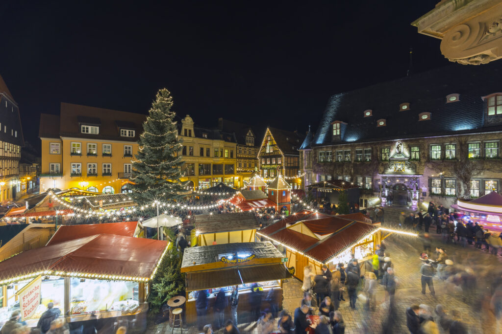 Lichterketten und Buden füllen den Marktplatz in Quedlinburg bei Nacht zur Weihnachtszeit.