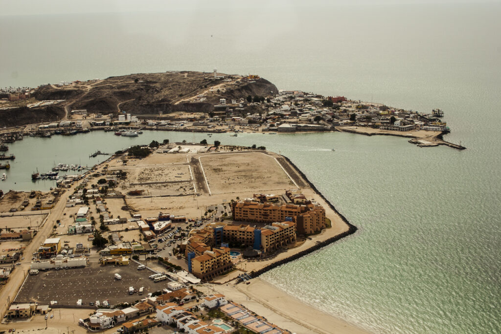 Luftaufnahme von Puerto Peñasco mit Hafen, Küste und sandiger Halbinsel am Meer.