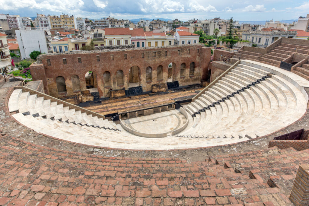 Blick in ein antikes Amphitheater mit hellen Sitzreihen und Backsteinmauer in Patras.