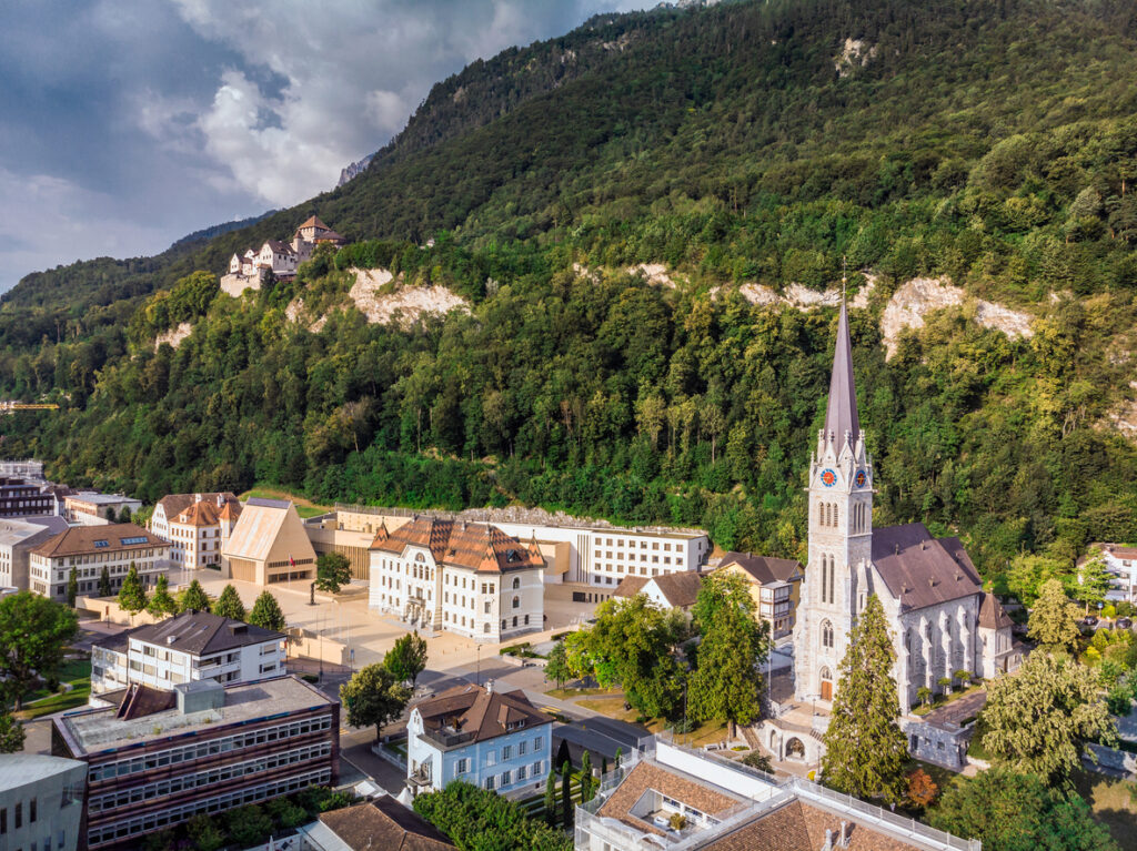 Panorama über eine Stadt mit Bergen und Wolken am Horizont.
