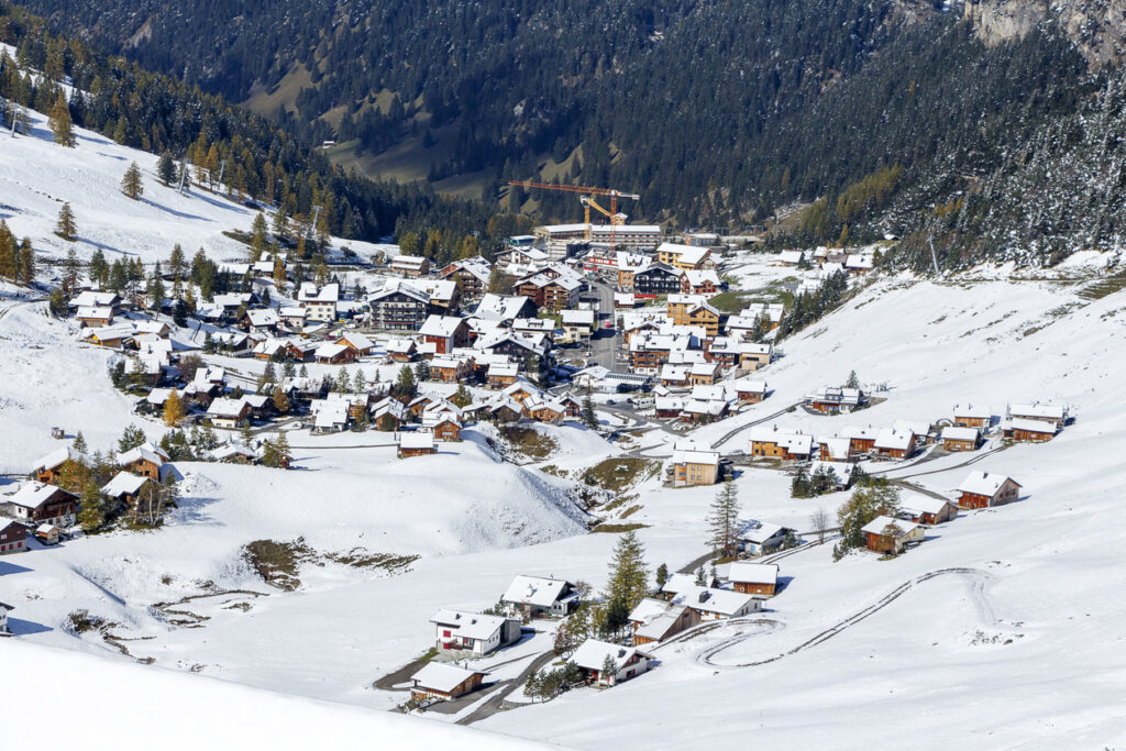 Schneebedecktes Bergdorf mit vielen Häusern in einem Tal.