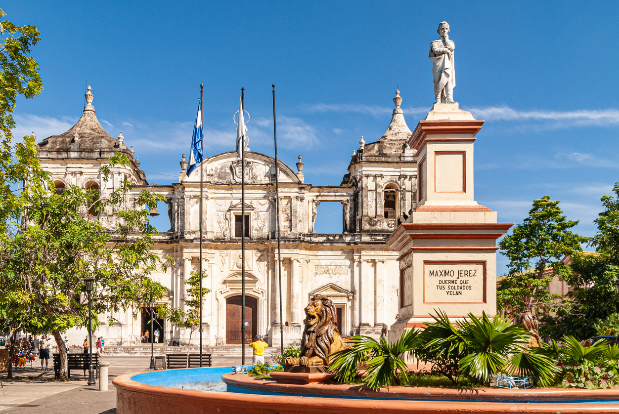 Monument und alte Kirche an einem Platz mit Bäumen in Nicaragua.