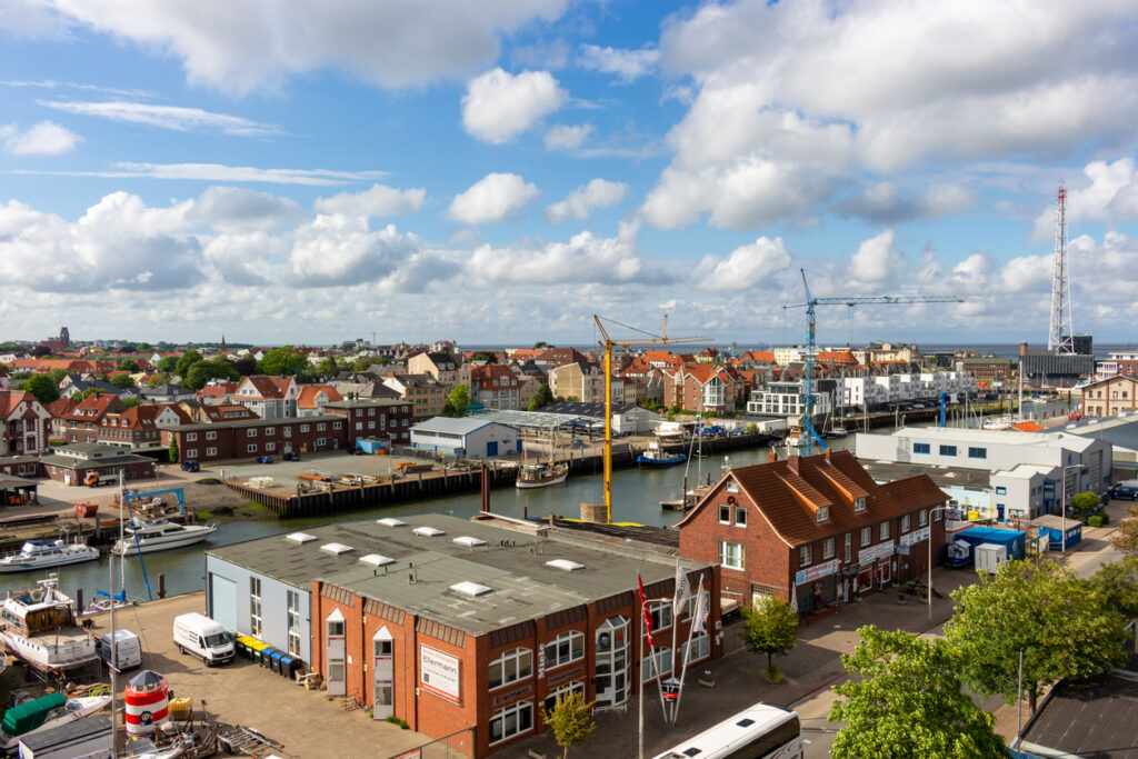 Eine erhöhte Ansicht auf Hafenbecken, Lagerhallen und Backsteingebäude unter einem leicht bewölkten Himmel.